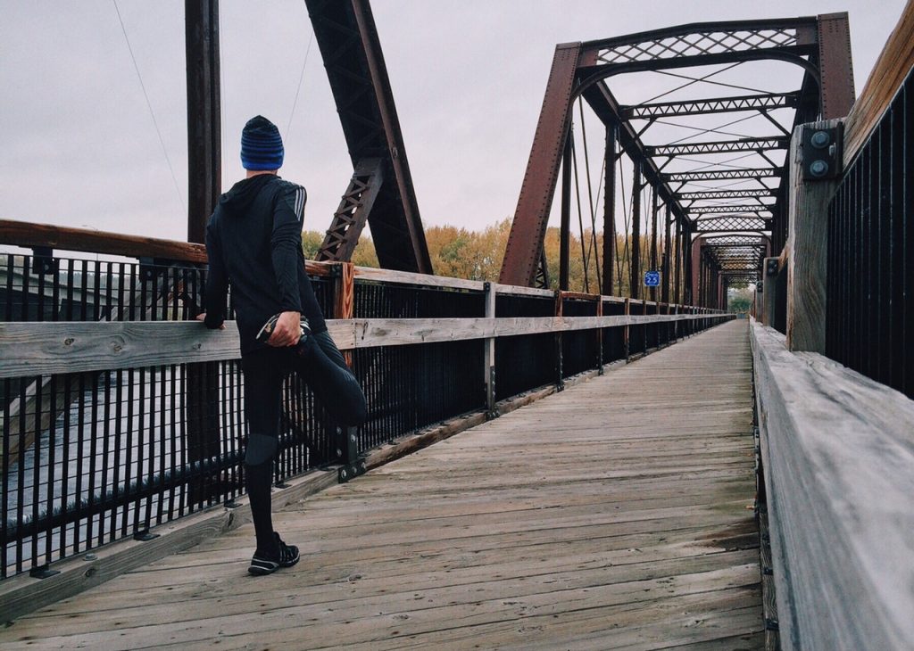 Man standing on a bridge preparing to run