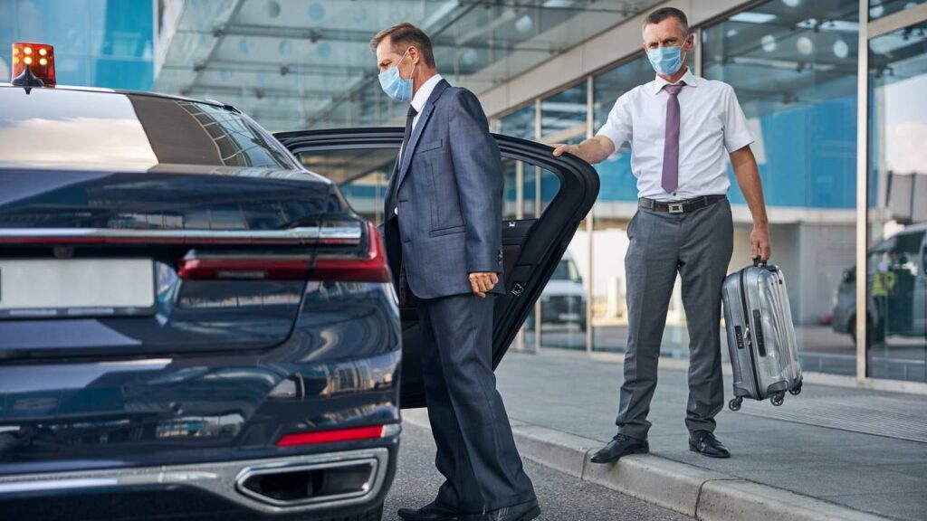 A chauffeur letting his passenger enter the car