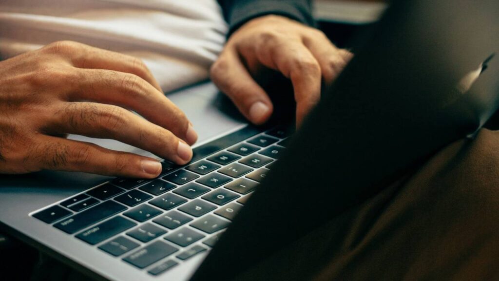 A close-up photo of a man using a silver laptop